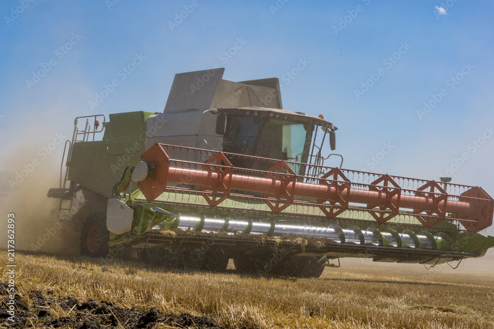 Obraz premium Close-up of a working harvester's at harvest time. A dust and straw fertilizer. Concept farming and agriculture.