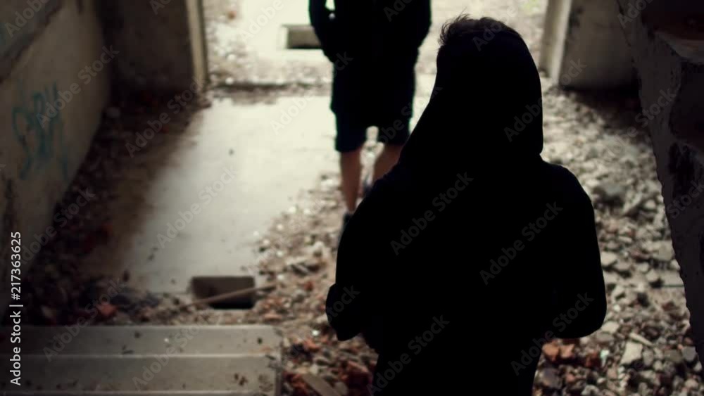 Two figures in the hoods meet in an abandoned building Two figures in the hoods meet in an abandoned building