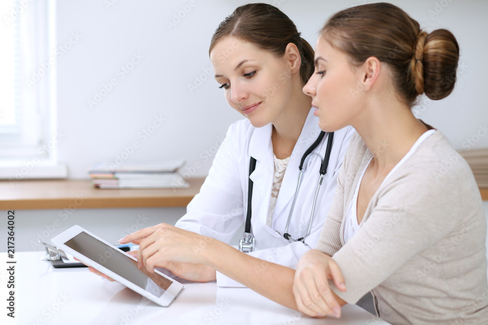 Doctor and patient having a pleasure talk while sitting at the desk at hospital office. Healthcare and medicine concept Doctor and patient having a pleasure talk while sitting at the desk at hospital office. Healthcare and medicine concept