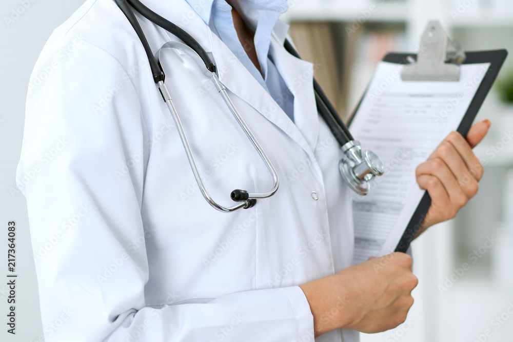 Closeup of unknown doctor woman standing with medication history records form at hospital. Health care, insurance and help concept Closeup of unknown doctor woman standing with medication history records form at hospital. Health care, insurance and help concept