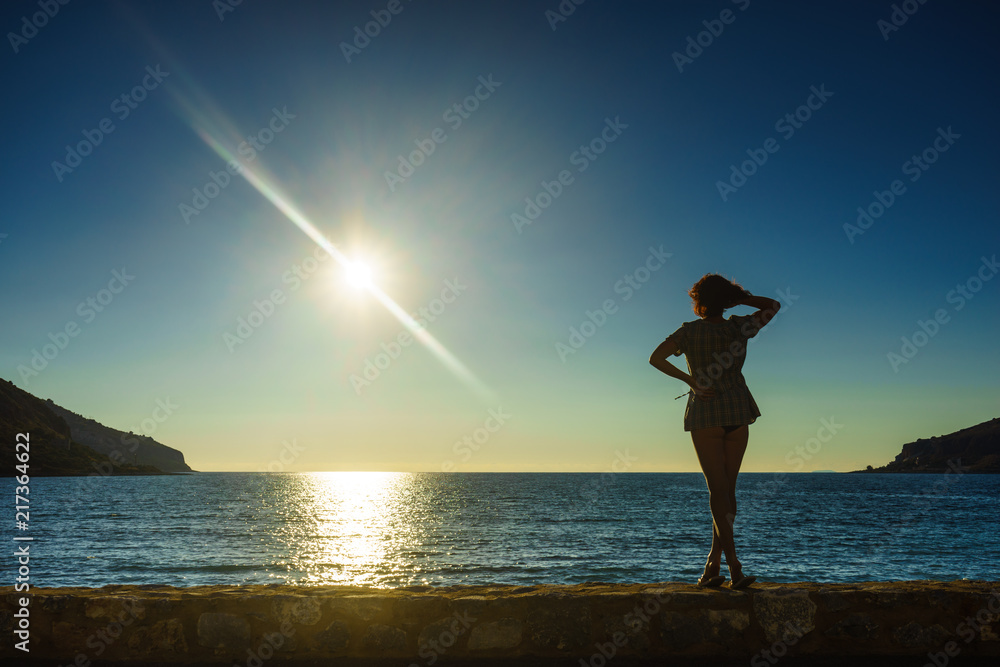 Tourist woman on sea shore enjoying sunset