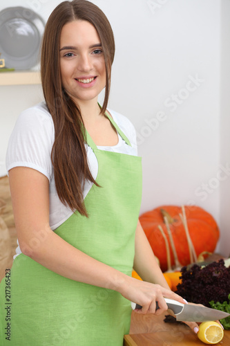 Young woman cooking in kitchen. Householding, tasty food and vegetarian in lifestyle concepts photo