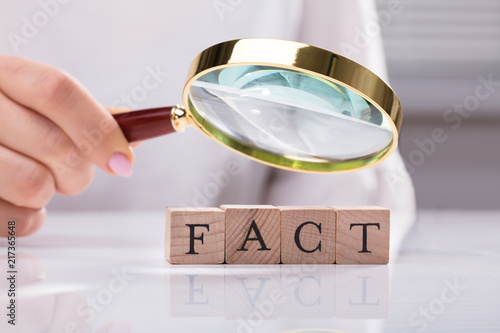 Foto Hand Holding Magnifying Glass Over Blocks Showing Fact Word