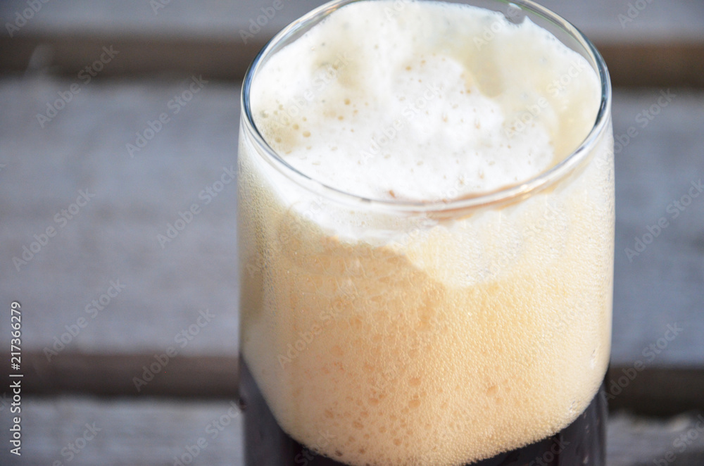 Glass of beer foam over wooden table Glass of beer foam over wooden table