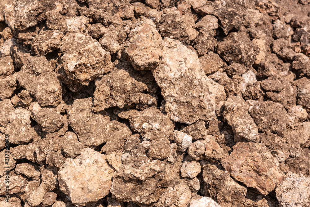Hunsur, Karnataka, India - November 1, 2013: Closeup of brown raw limestone with with spots of lime visible. To be crushed and heated in kiln.