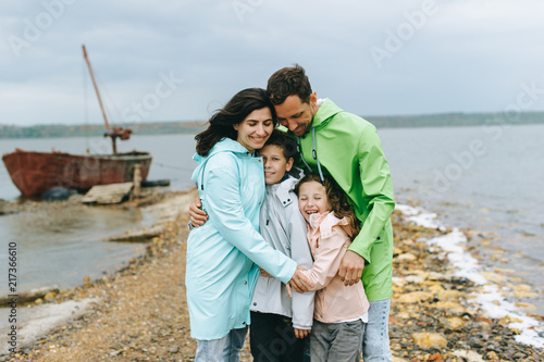 Beautiful family portrait dressed in colorful raincoat near the lake