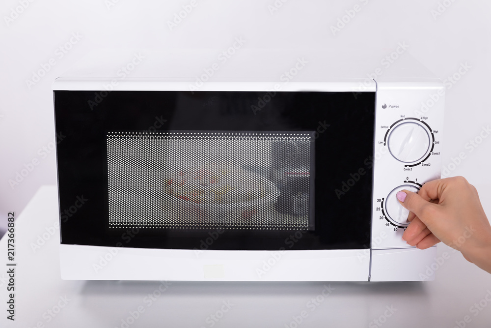 Fototapeta premium Woman Using Microwave Oven For Preparing Food
