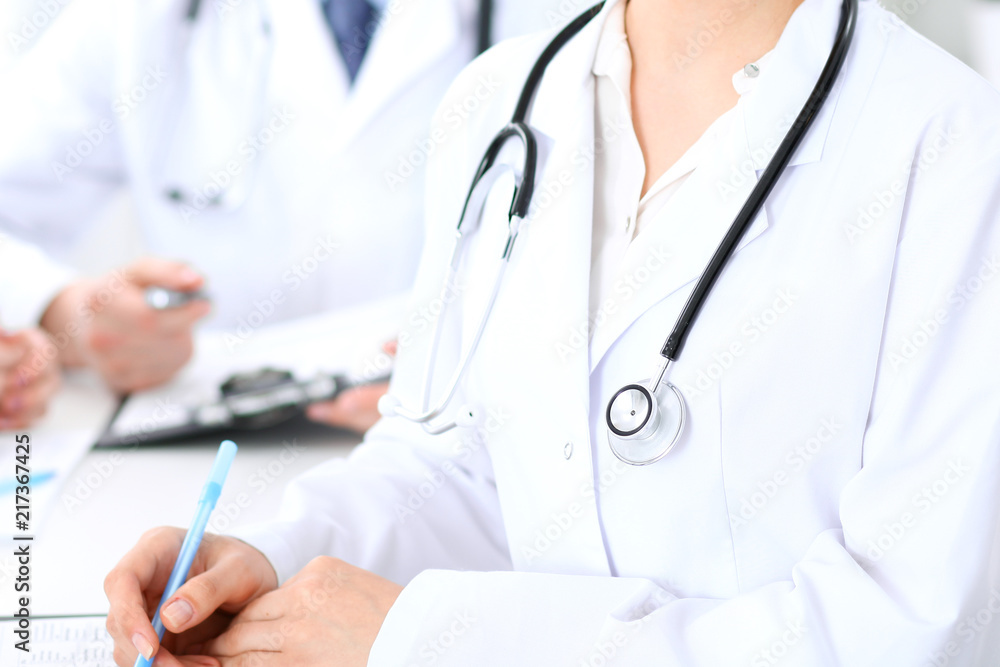 Group of unknown doctors working at hospital while sitting at the table. Teamwork and success concept in medicine Group of unknown doctors working at hospital while sitting at the table. Teamwork and success concept in medicine