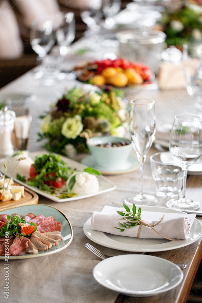 Neatly twisted into a tube dining room napkin decorated with a sprig of pistachio. Wedding Banquet or gala dinner. The chairs and table for guests, served with cutlery and crockery. party on terrace Neatly twisted into a tube dining room napkin decorated with a sprig of pistachio. Wedding Banquet or gala dinner. The chairs and table for guests, served with cutlery and crockery. party on terrace