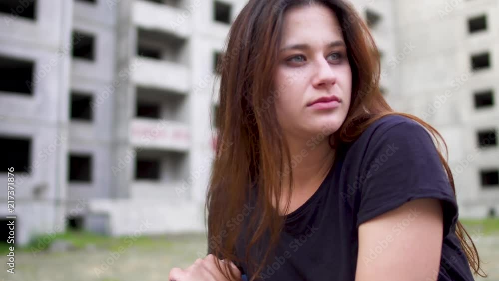 Nervous brunette girl is sitting near high building Nervous brunette girl is sitting near high building