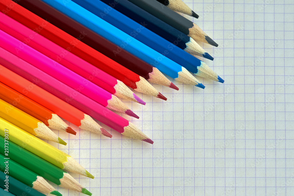 Colored pencils on a checked notebook. Close-up, top view Colored pencils on a checked notebook. Close-up, top view