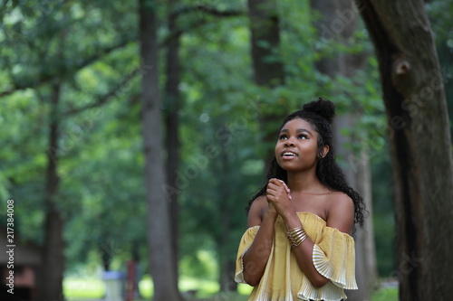 Young ethnic woman with praying hands looking up