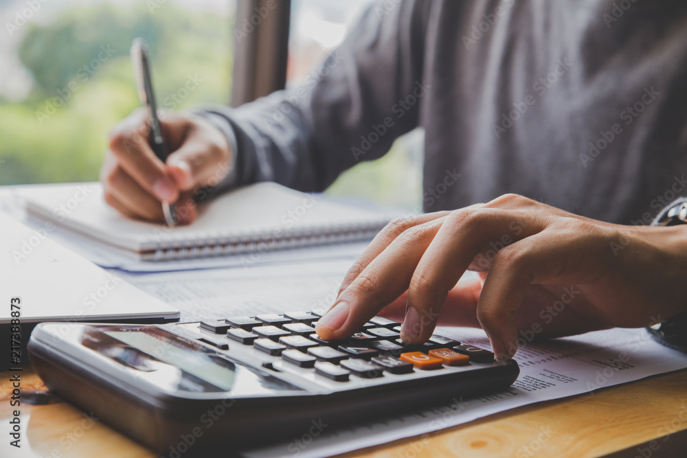 Fototapeta premium Man with calculator counting making notes at office hand is writes in a notebook