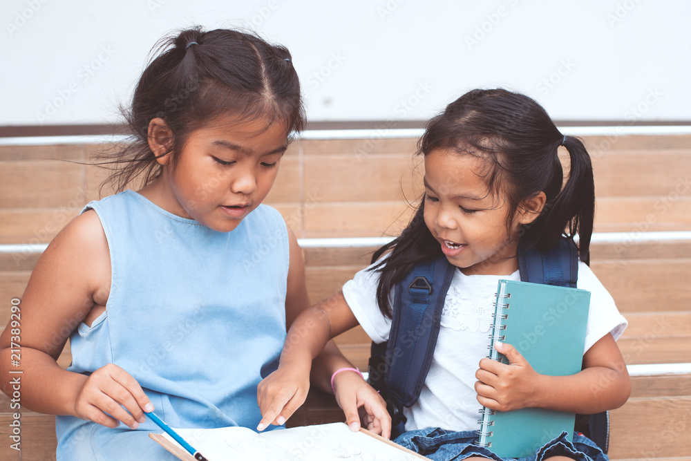 Back to school. Cute asian child girl and her sister reading a book  together with fun and happiness