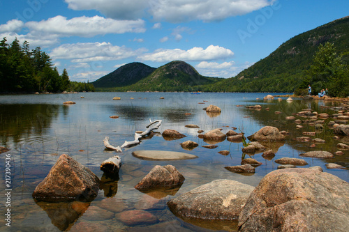People in canoe enjoying Jordan Pond in Bar Harbor surrounded by mountains on a warm summer day under a beautiful sky
