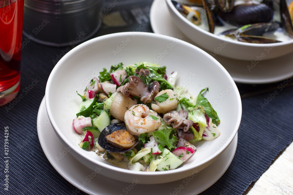 Warm salad with seafood mussels, octopus and fresh vegetables in deep plate on the table Warm salad with seafood mussels, octopus and fresh vegetables in deep plate on the table