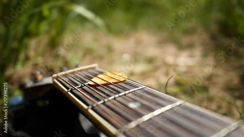 Acoustic guitar with wooden finish in slow motion in nature and grassy riverside.