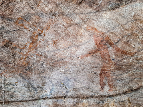 Prehistoric painting of men in actions on rock painted with red colour
