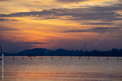 View of twilight sky reflected on water surface in Songkhla Lake  Southern Thailand with mountains in background.