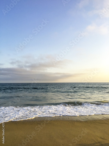 Beach Ocean Waves Background With Blue Cloudscape During Sunset.