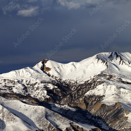 Winter mountains at sun evening and dark clouds photo