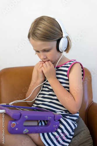 Female child watching her tablet with white head phones on