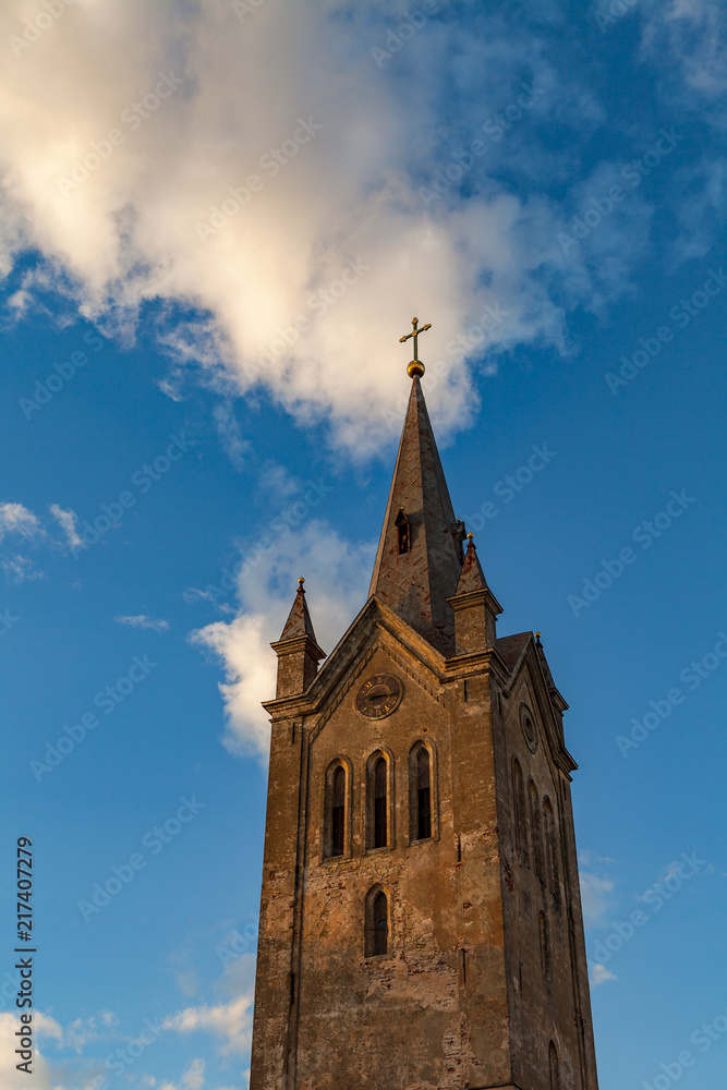 Fototapeta premium Tower of the old church lit by sunset light with dramatic clouds. Cesis, Latvia.