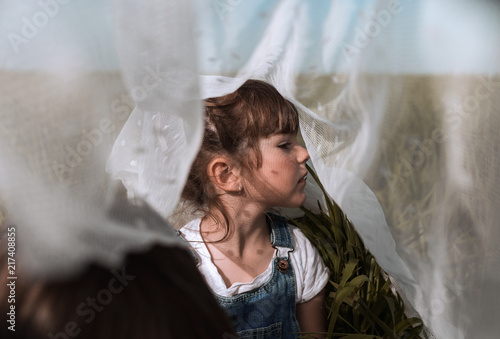 Thoughtful girl sitting under mesh netting outdoors