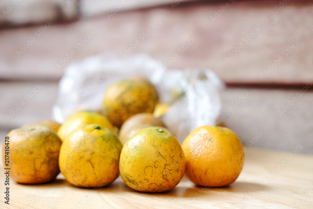 Fresh oranges fruits a transparen plastic bag on wooden background.