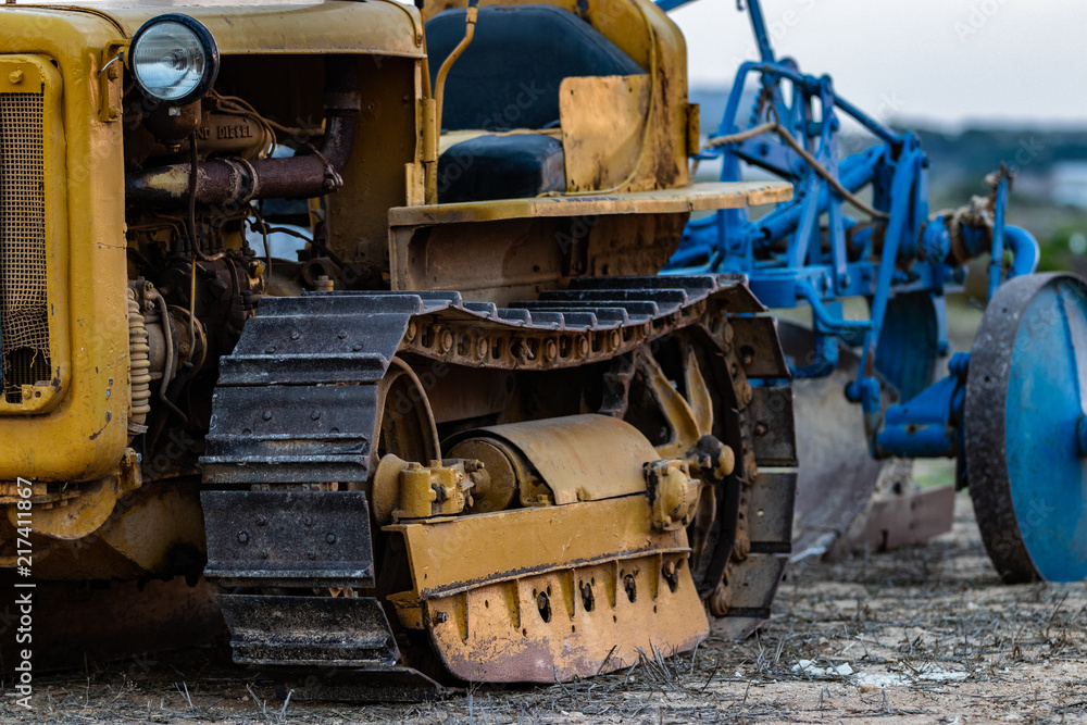 Fototapeta premium Caterpillar Old Tractor in a Field during Sunset