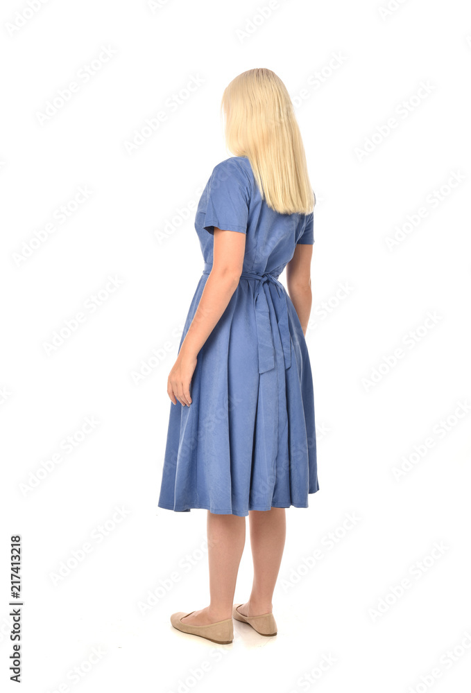 full length portrait of blonde girl wearing blue dress. standing pose with back to the camera. isolated on white studio background. full length portrait of blonde girl wearing blue dress. standing pose with back to the camera. isolated on white studio background.