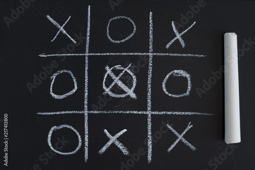 Fotografija O X Game on black chalk board