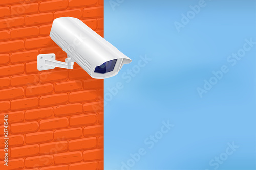 Security camera on red brick wall. With blue sky