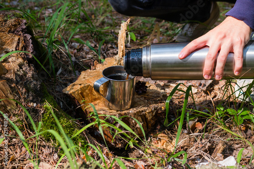 hiker pours tea from a thermos in a summer forest