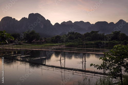 Glorious sunset over the mountains that dominate Vang Vieng overlooking the Nam Song river and the wooden bridge, Laos