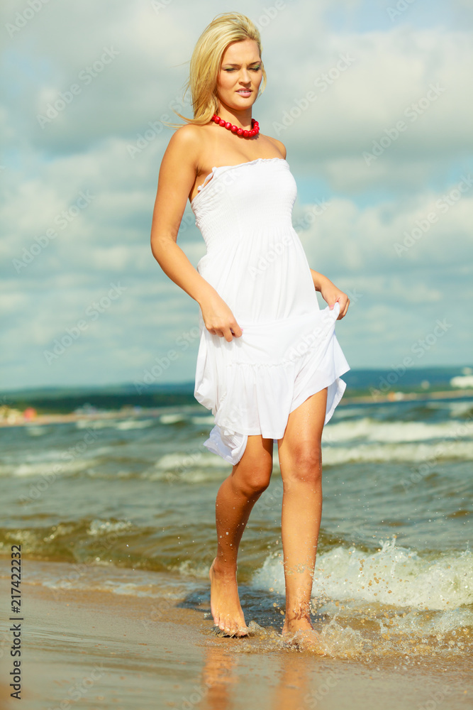 Blonde woman wearing dress walking in water