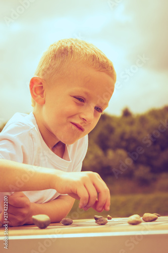 Little boy clever child playing checkers in park