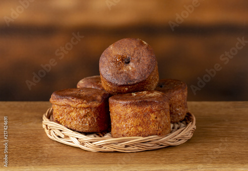 Small cupcakes without cream on a wooden basket. Background is brown. Copy space.