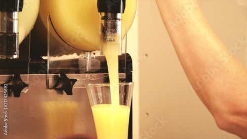 Hand pouring a frozen lemon slush in a store.