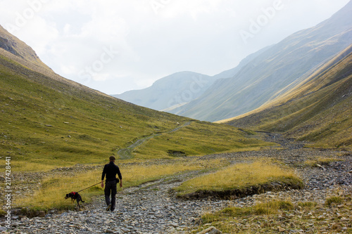 Men with dog walking on a trail in the mountains