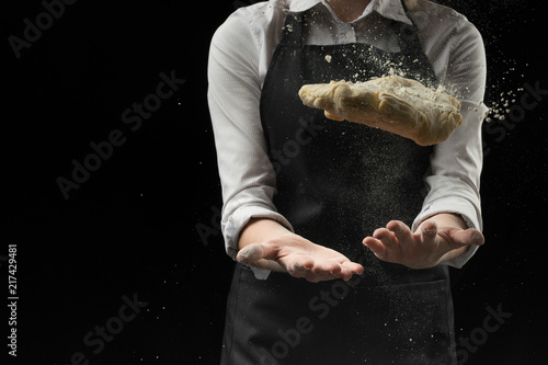 Chef cooked dough for pizza, rolls, pasta on a dark background. Baker's bakery