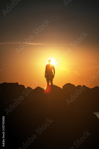 Silhouette of a girl on the beach overlooking the ocean during colorful sunset light with lens flare in summer holidays. Danish Coastline. Lonstrup in North Jutland in Denmark, Skagerrak, North Sea