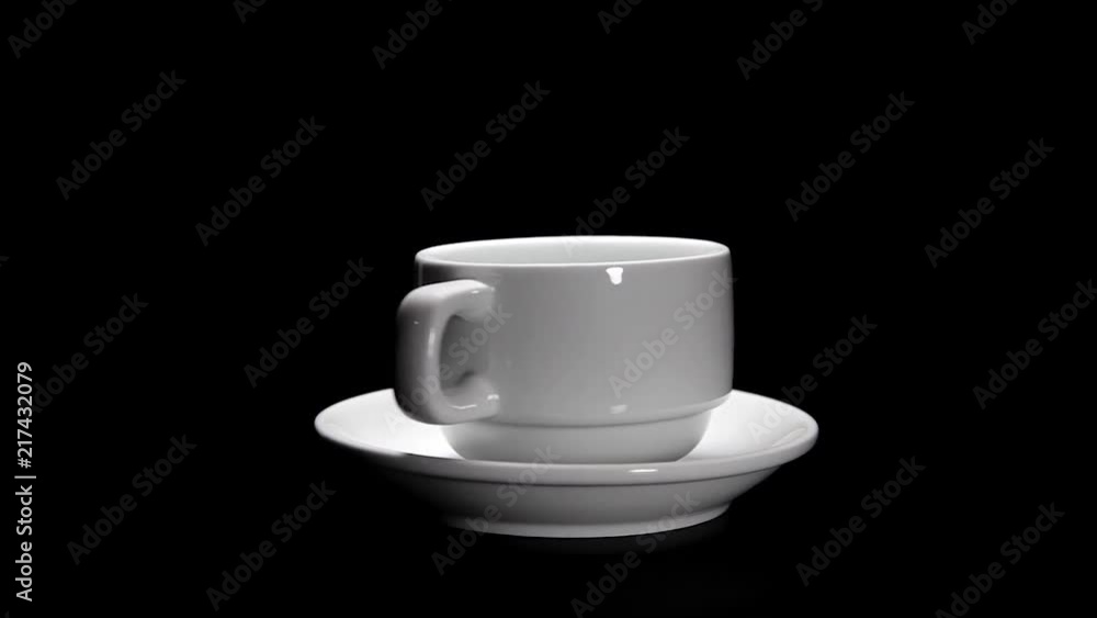 White cup and a plate for coffee, rotate on a black background. White cup and a plate for coffee, rotate on a black background.