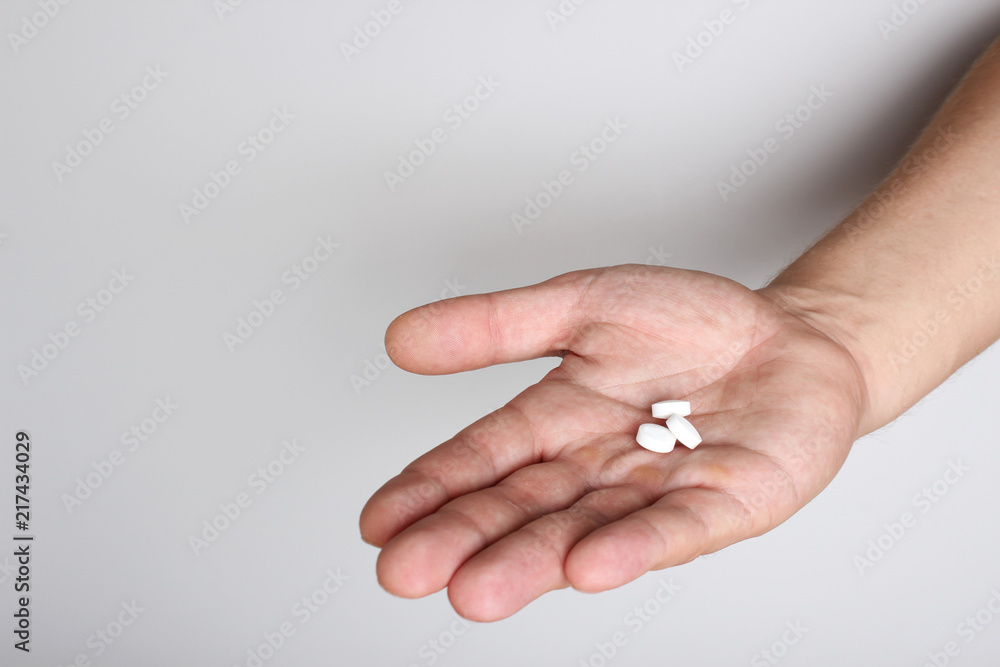 white pills in a hand on a light background white pills in a hand on a light background