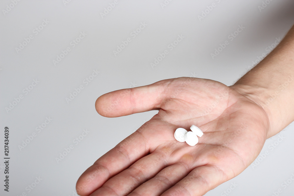 white pills in a hand on a light background