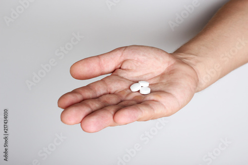 white pills in a hand on a light background