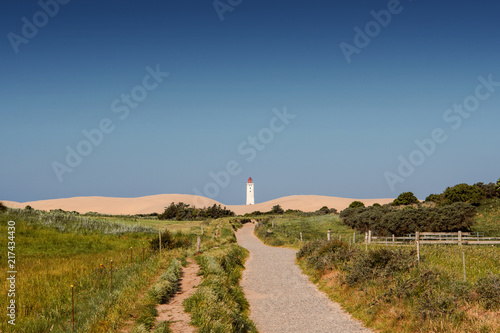 Famous Lighthouse landmark and travel spot with epic sand dunes and grass landscape in beautiful summer sunset. Rubjerg Knude Lighthouse, Lønstrup in North Jutland in Denmark, Skagerrak, North Sea
