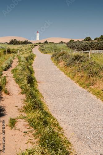 Beautiful danish nature landscape view of sand dunes and a white lighthouse framed by blurry trees. Rubjerg Knude Lighthouse, Lønstrup in North Jutland in Denmark, Skagerrak, North Sea