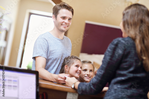 Happy family checking in hotel at reception desk