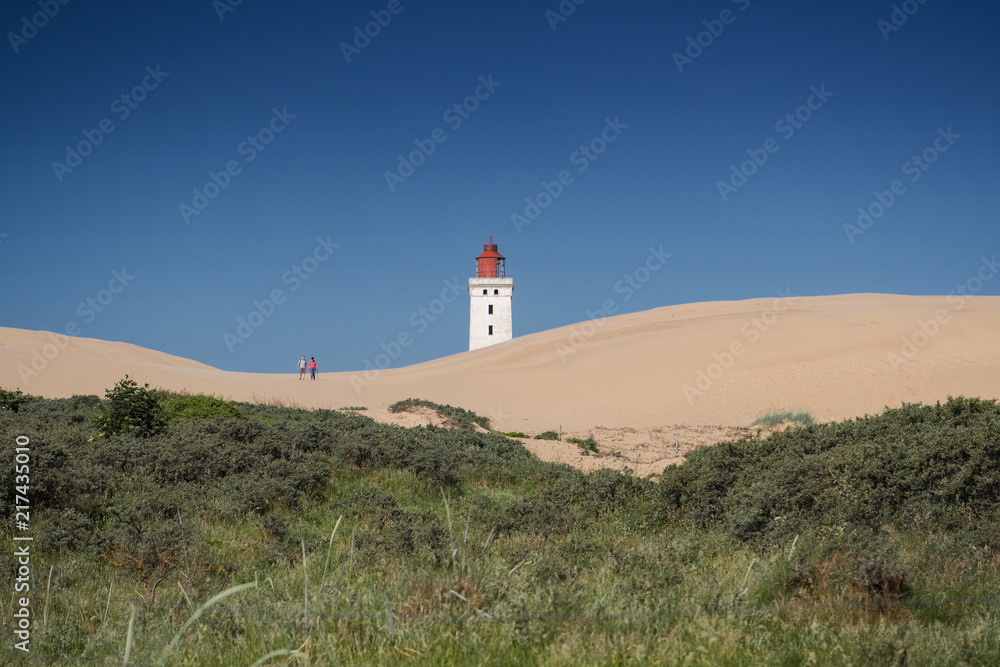 Endless white sand dunes and the famous danish lighthouse landmark during daytime and blue sky in summer vacation. Rubjerg Knude Lighthouse, Lønstrup in North Jutland in Denmark, Skagerrak, North Sea